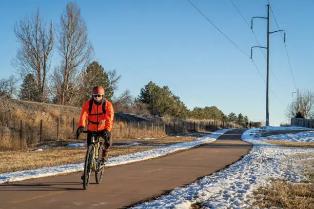 senior male cyclist is riding a touring bike in winter scenery in Fort Collins, Colorado - Power Trail runs along railroad and power line