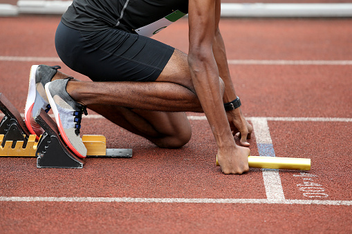 Asia male teenager getting ready starting to run on track in stadium, backshot view low angle