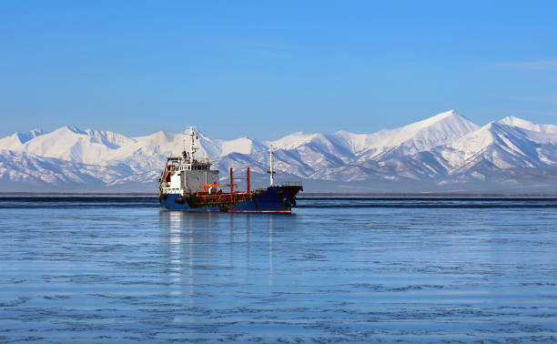Sea vessel in the bay in winter against the backdrop of snow-capped mountains