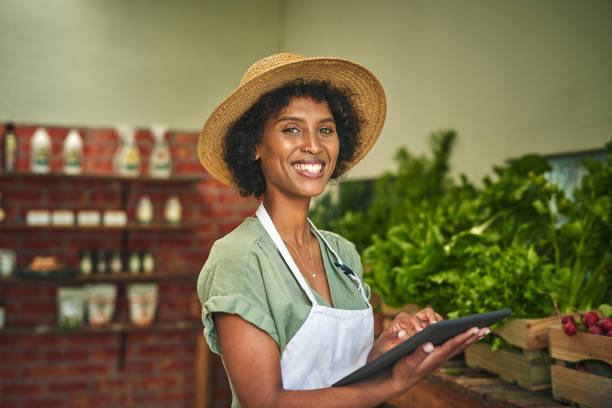 tiro de uma jovem usando um tablet digital enquanto trabalhava em um mercado de agricultores - organic farmers market market vegetable - fotografias e filmes do acervo