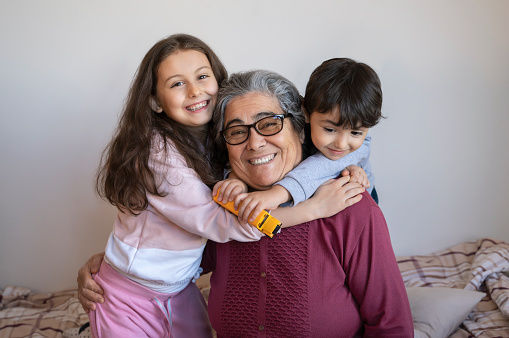 Senior woman sitting on a sofa with her granddaughter and grandson, Home interior