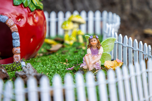 A small fairy relaxes in an outdoor miniature garden.