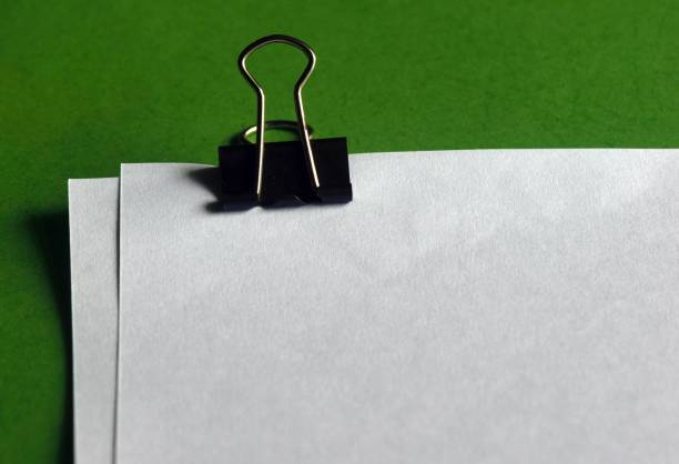 istock Paperclip, white papers for note on green paper background 1373235722