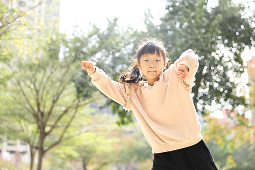 a Asian girl dancing in a park.