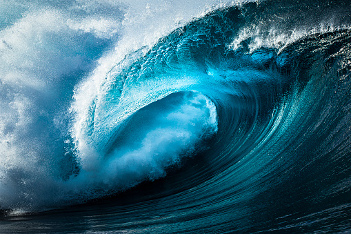 Close up detail of bright blue wave breaking powerfully on a reef