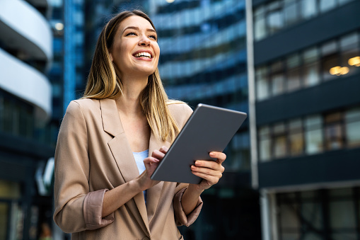 Portrait of a successful young business woman using digital tablet in front of modern business building