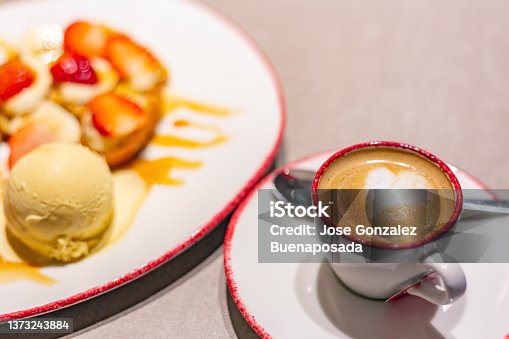 istock Cup of foamy coffee and dessert with croissant, banana, strawberries and ice cream. Delicious and appetizing 1373243884