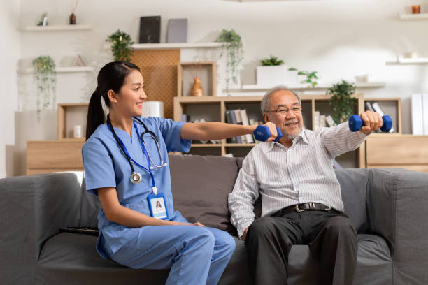 la doctora asiática aconseja a la paciente anciana al fisioterapeuta que haga ejercicio con mancuernas en casa. enfermera sonriente que ayuda al paciente mayor a hacer ejercicio de entrenamiento para fortalecer los músculos. enfermería fisioterapeuta. - desintoxicación fotografías e imágenes de stock