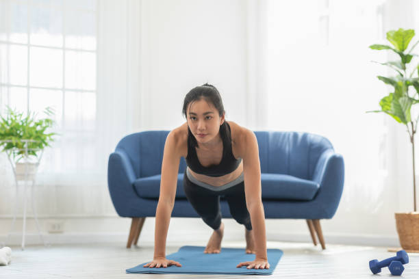 istock Asian girl doing push ups workout exercise on exercise mats concentration on shoulder muscle at home.Athletic female pushing up training with cardio exercise in living room.Self workout concept 1373245802