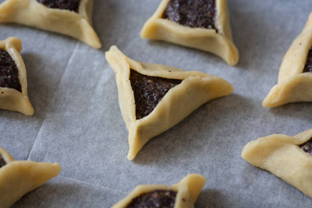 미리 구운 "하만 포켓", 또한 하만타셴으로 알려진, 아슈케나지 유대인 삼각형 채워진 포켓 쿠키, 일반적으로 푸림의 유대인 휴가와 관련된, 양귀비 씨앗으로 가득 - purim high angle view cookie food 뉴스 사진 이미지