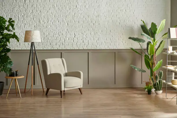 Photo of Room wall concept, brick and classic style, clock armchair lamp and green plant botanic interior decor, brown parquet and carpet.