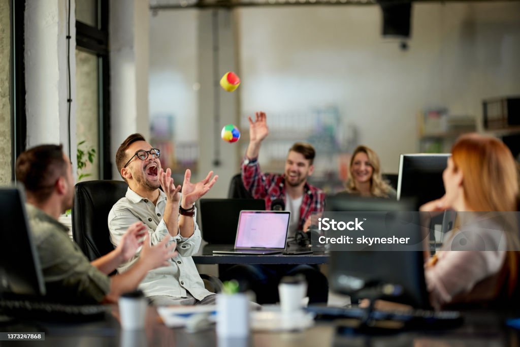 Playful programmers having fun on a break in the office. Group of cheerful programmers having fun while throwing balls during a break in the office. Office Stock Photo