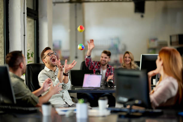 Playful programmers having fun on a break in the office. Group of cheerful programmers having fun while throwing balls during a break in the office. corporate culture stock pictures, royalty-free photos & images