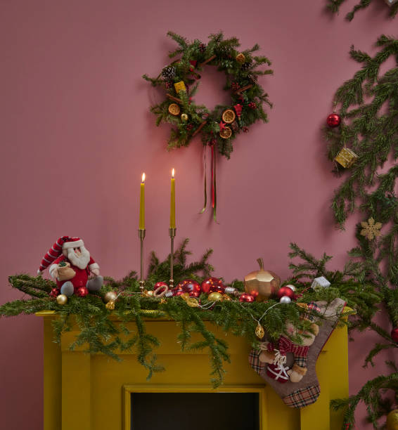 istock Close up fireplace with pine branch decoration, pink wall background with candle and gift box style. 1373249372