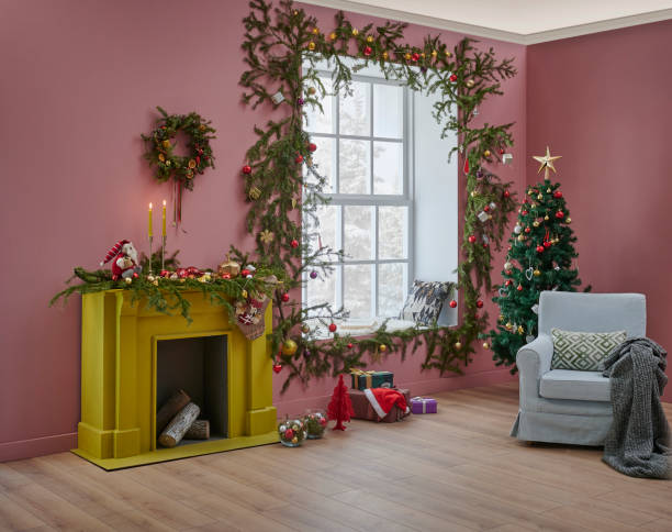istock Christmas tree and yellow fireplace in front of the decorative windows, interior room, pine branch decoration, gift box and furniture chair and sofa design. 1373249561