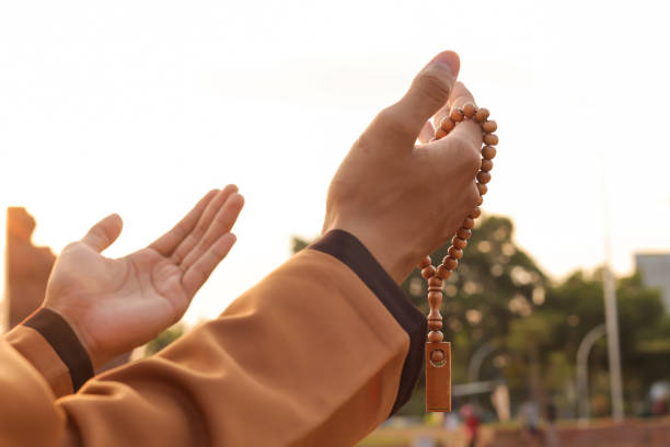 male hand praying with islamic beads stock photo