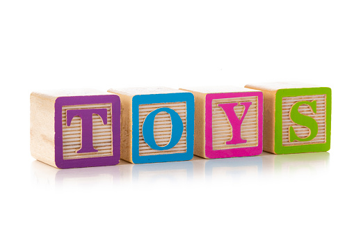 Front view of a group of multicolored wooden block shapes arranged side by side with TOYS letters isolated on white background