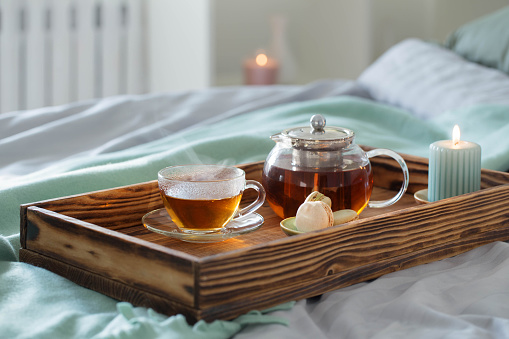 tea on wooden tray on bed at home