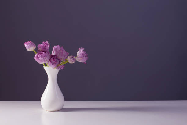 istock violet tulips in white vase on background gray wall 1373252872