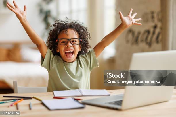 Little African American School Boy Raising Hands Up With Excitement During Home Distance Education Stock Photo - Download Image Now