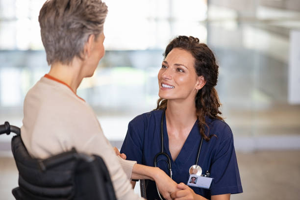 Friendly nurse talking with disabled senior patient