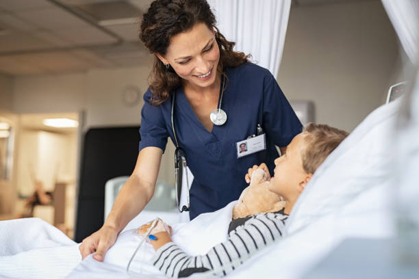 adorável enfermeira cuidar de criança na clínica - hospital patient bed nurse - fotografias e filmes do acervo