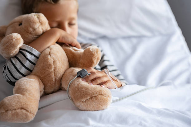 istock Little boy sleeping in hospital bed with teddy bear 1373259856