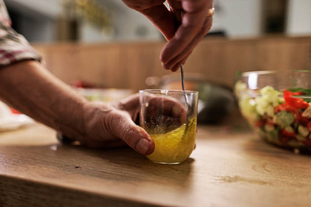 seniorenpaar bereitet zu hause einen gesunden gemüsesalat zu. - zitronensaft stock-fotos und bilder