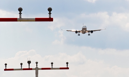 An aircraft flies low over runway lights, another aircraft follows in distant background.
This image is part of an airport series.