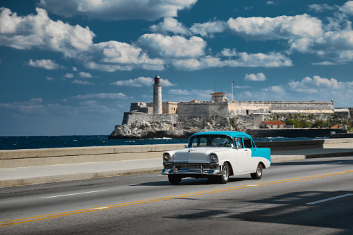 Retro car on the embankment of Havana, Cuba. El morro castle and lighthouse on background, shot with panning.