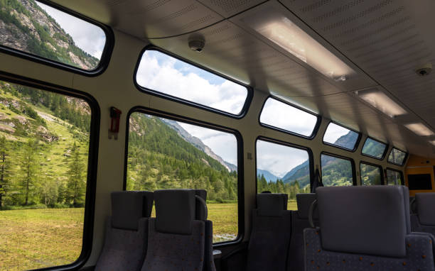 istock Swiss train interior with comfortable chairs, on two rows, a table and mountain, foresrs view on window. Public transport. Passenger train interior. 1373263348