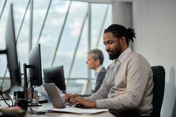 istock Smiling black businessman working on laptop in the office. 1373263566