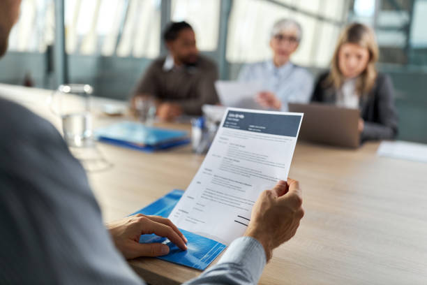 Holding resume on job interview! Close up of unrecognizable male candidate holding his CV during job interview in the office. job search stock pictures, royalty-free photos & images