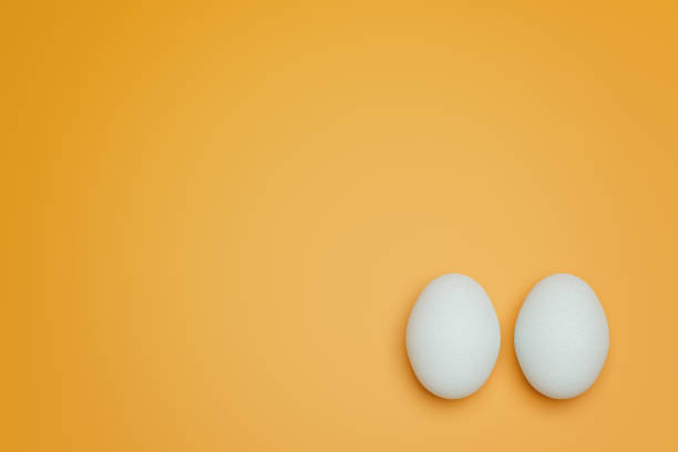 istock Two white chicken eggs on yellow background top view. Creative food minimalistic background. 1373264641