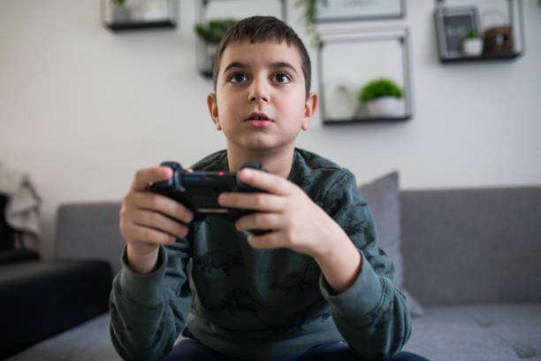 Boy playing video games sitting on the sofa at home stock photo