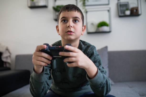 chłopiec grający w gry wideo siedzący na kanapie w domu - playing video game little boys playful zdjęcia i obrazy z banku zdjęć