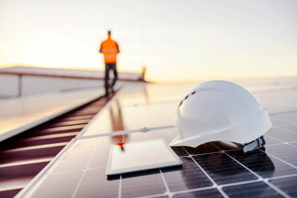 a helmet and tablet on solar panel on rooftop. - manual worker portrait helmet technology imagens e fotografias de stock