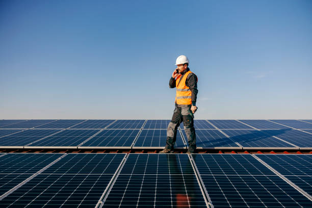 istock A repairman talking on the phone while standing on rooftop surrounded by solar panels. 1373265097