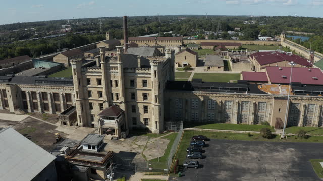 Aerial view of the old and abandoned Joliet prison or jail, a historic site. Drone flying backward to capture panoramic view of the location. Streets of Naperville Illinois and Joliet Prison.