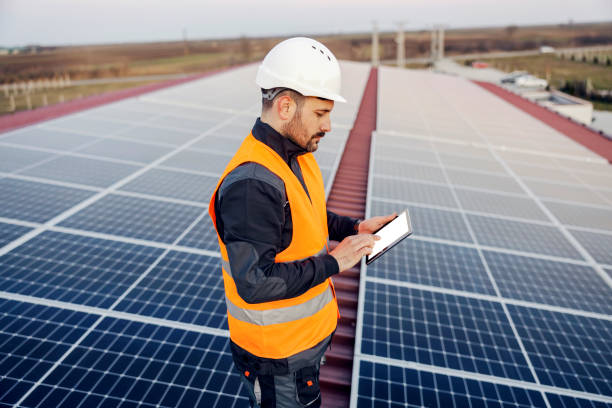 istock A handyman scrolling on tablet and checking on panels on roof. 1373265788