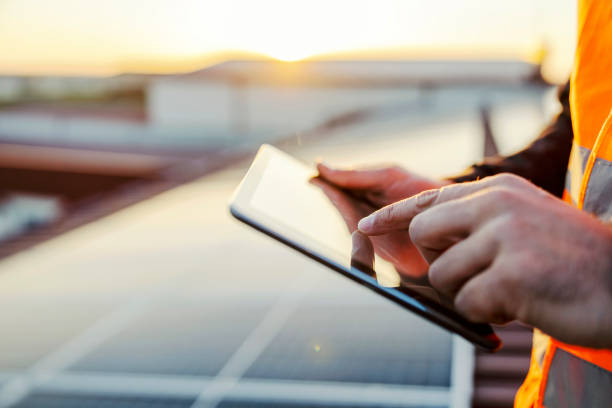 feche a mão rolando no tablet e verificando em painéis solares. - solar panel innovation renewable energy alternative energy - fotografias e filmes do acervo