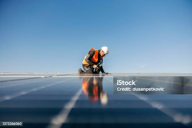 Worker Kneeling And Sets Solar Panel Stock Photo - Download Image Now - Solar Power Station, Solar Energy, Sun