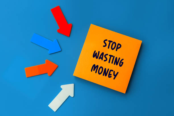 Stop Wasting Money - concept of text on sticky note. Orange square sticky note and colorful arrows on blue background, top view