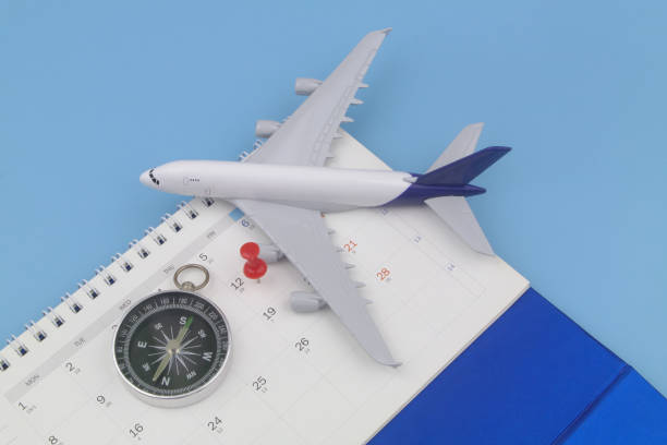istock Airplane model with black compass and push pin on calendar page. 1373266324