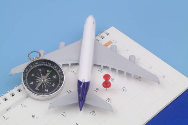 istock Airplane model with black compass and push pin on calendar page. 1373266336