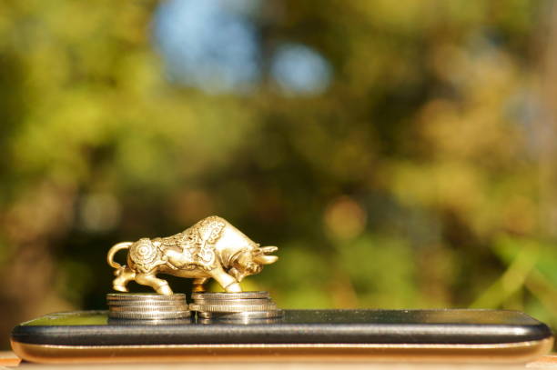 istock Bull figurine with coins on a mobile phone. 1373266886