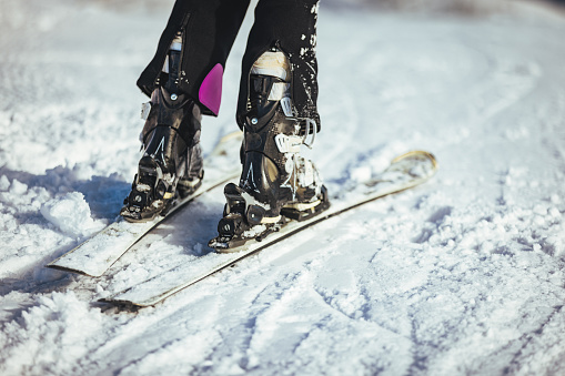 Close-up of an unrecognizable skier in boots skiing on top of a mountain.