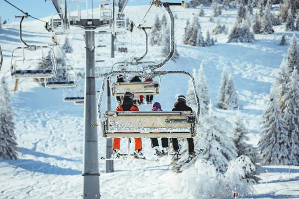 Photo of S ki lift with skiers in front of a blue sky.