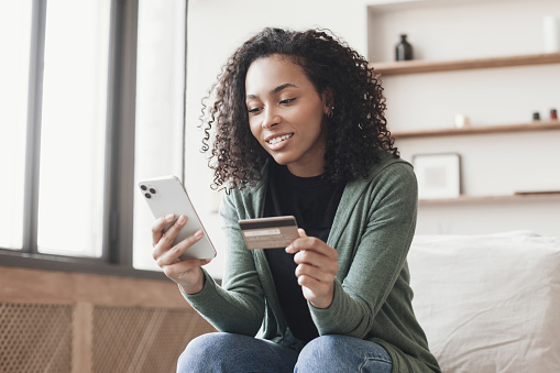 African american girl using smart phone at home. Online shopping, internet banking concept