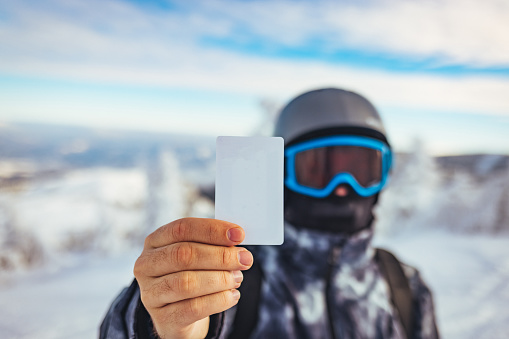 Young man holding blank ski lift pass looking